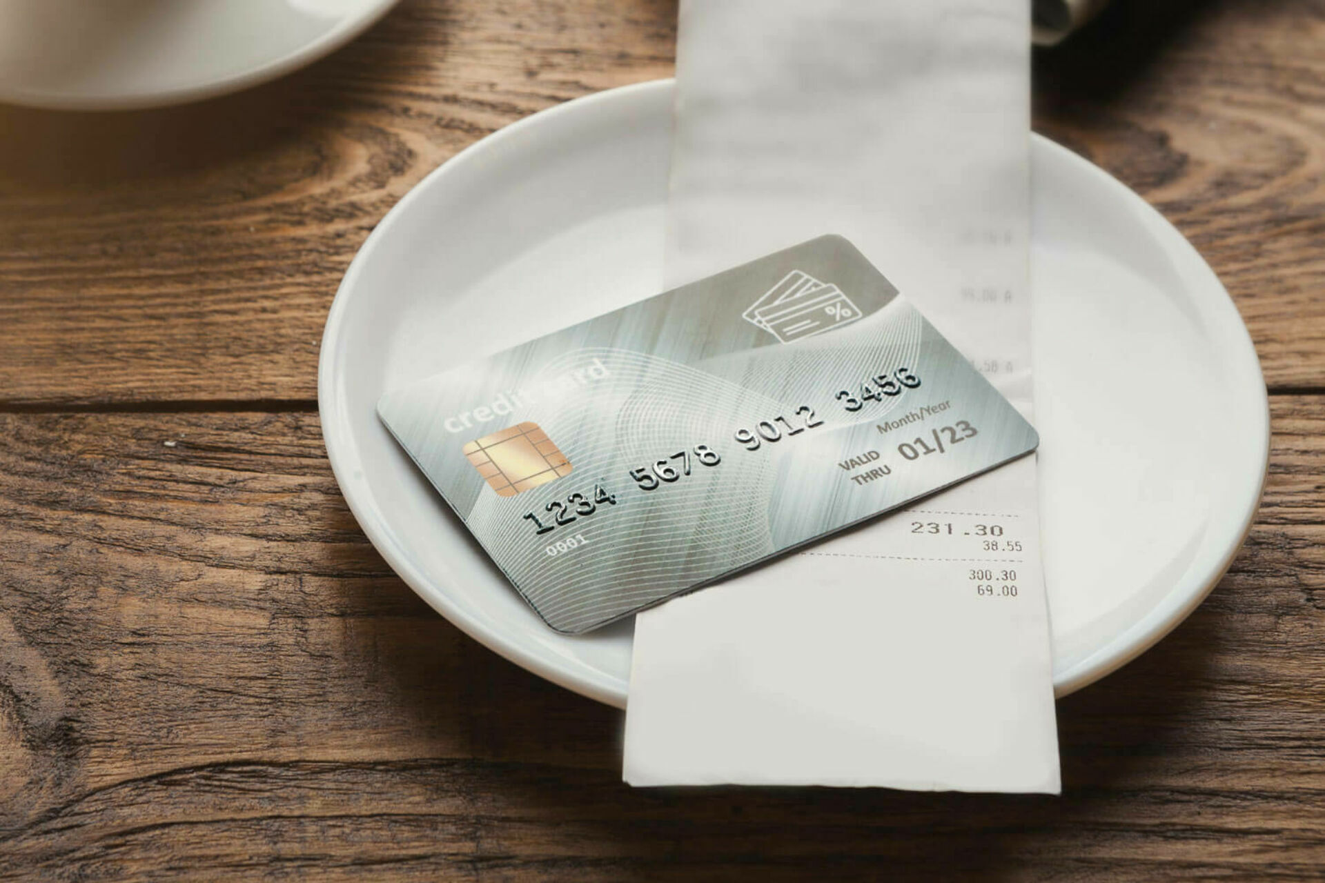 Credit card on small plate in restaurant with receipt 1500x1000