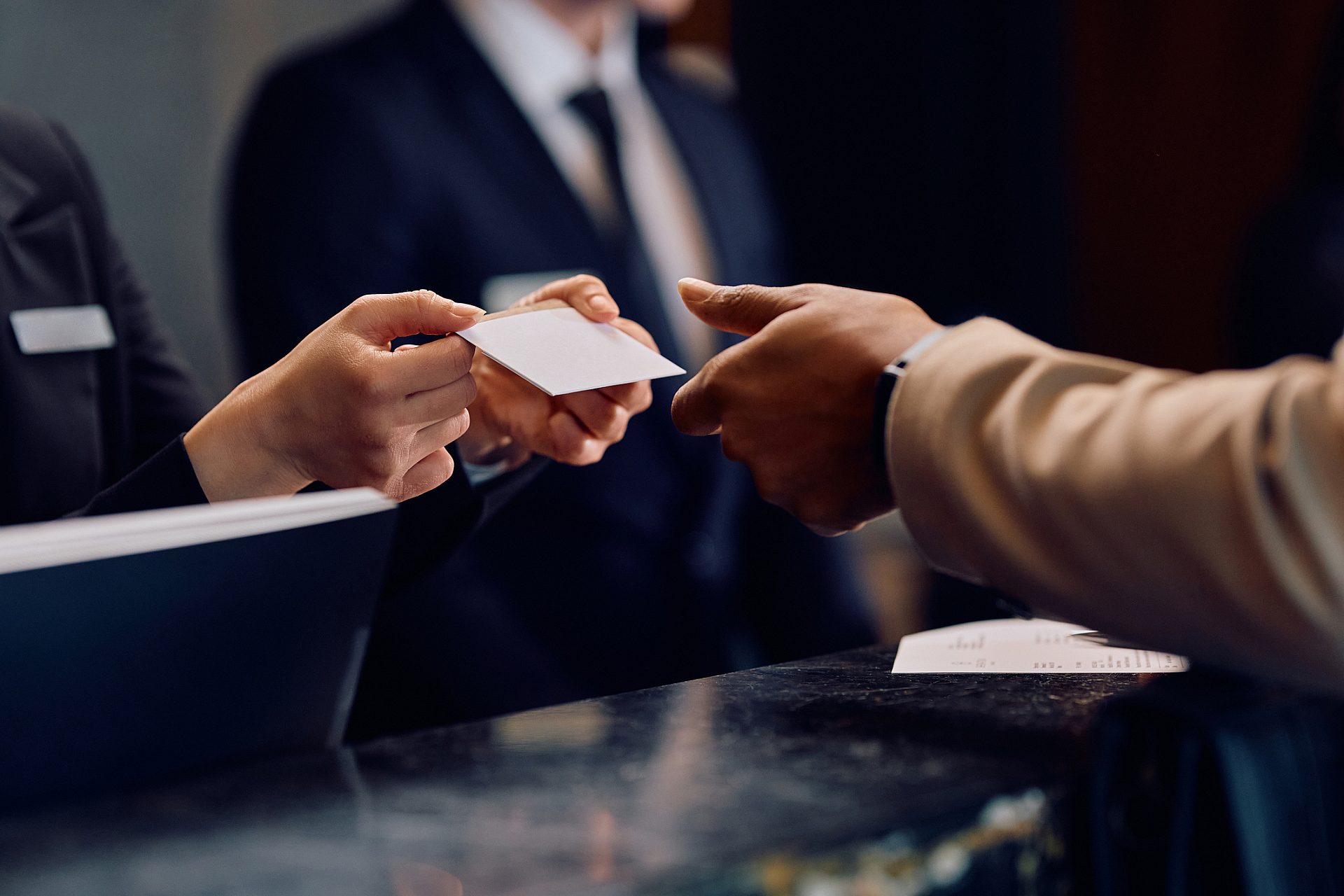 Close up of hotel receptionist giving room cardkey to African American hotel guest.