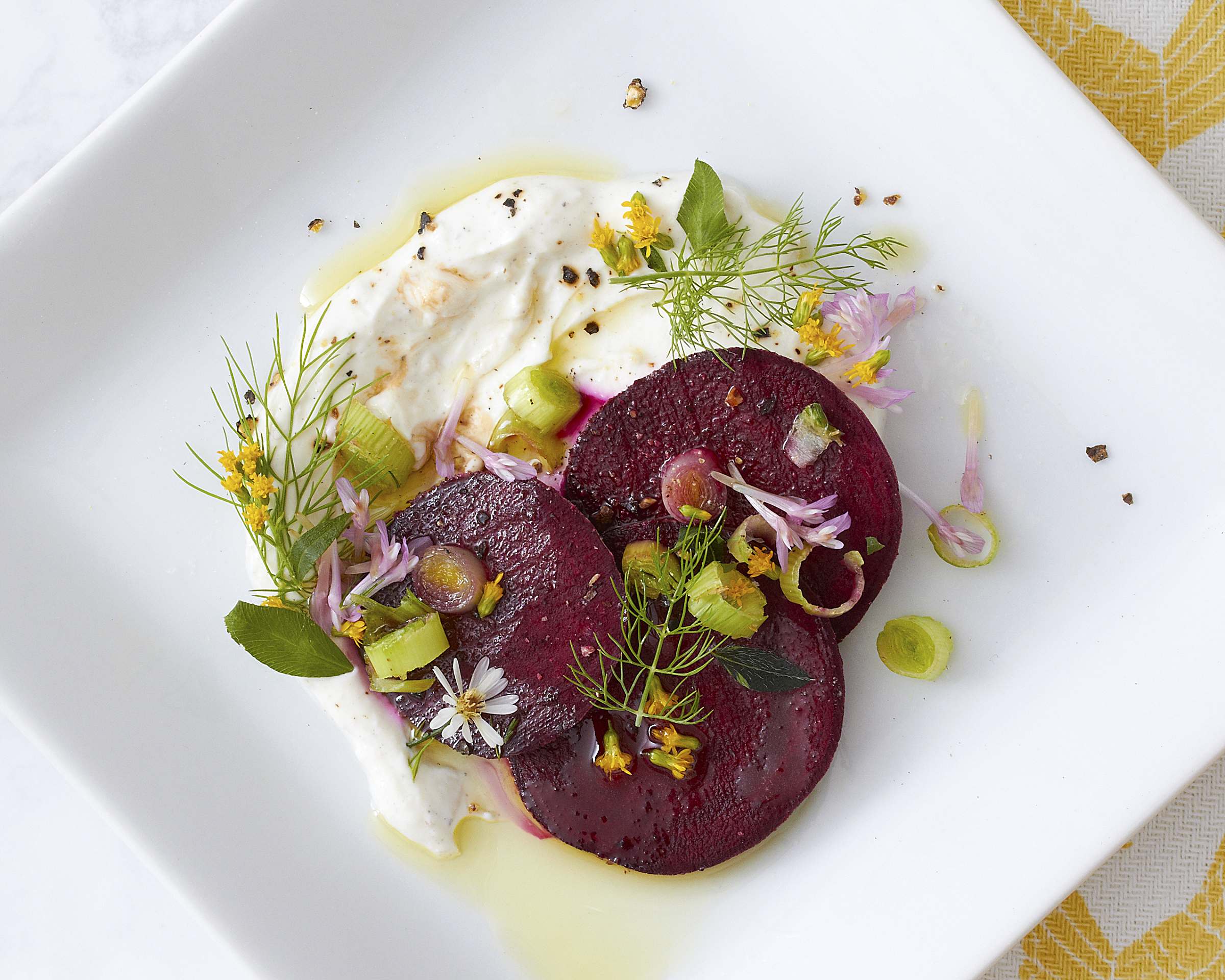 An artfully plated beet salad dish on a white square plate.