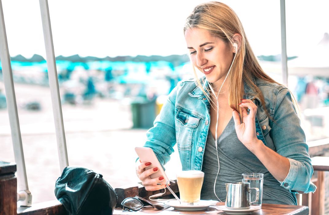 Jonge vrouw in restaurant met koffie en smartphone