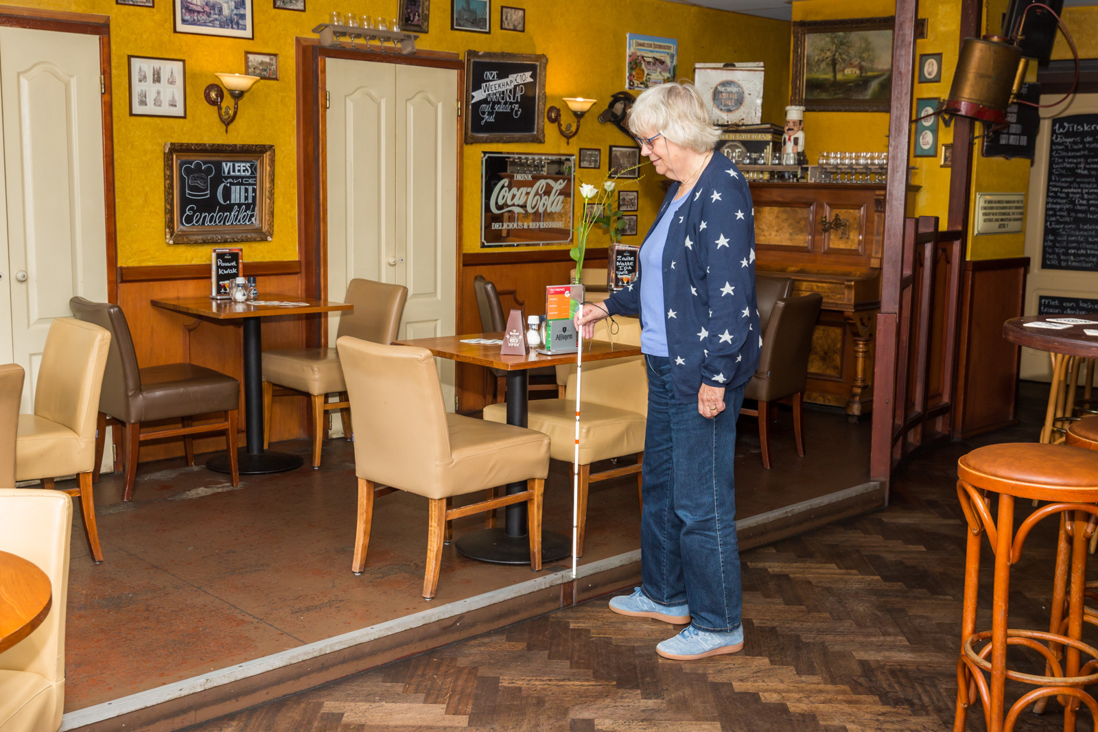 Gast met blindenstok in cafe met drempel
